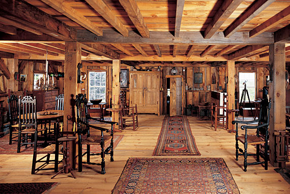 The upper level of the barn is divided by the supporting beams into small dining and sitting areas. The couple has gathered a grand array of banister-back and turned 