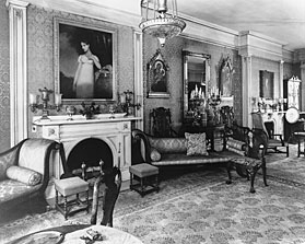1954 photograph showing the room without the doors. The glass chimneys and prisms of the chandelier were also removed. The couple had the doors reproduced and the chandelier restored.