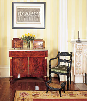 An Anglo-Indian ebonywood chair in the Regency taste sits beside a New York sideboard cabinet, 1825. The picture is a posthumous reprinting, 1803-1807 of a Giovanni Battista Piranesi (1720-1778) copperplate etching depicting a bas relief from an antique marble vase in the Villa Borghese. Piranesi, a major Italian printmaker, architect and antiquarian, produced a series of copperplate etchings during the second half of the eighteenth century. detailing the views and antiquities of Rome, which encouraged the spread of Neoclassical design across the continent.