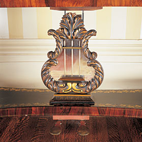 The lyre, as depicted here on the base of the square piano, was a popular motif in the Empire period, and a particular favorite of Duncan Phyfe (1768-1854). Phyfe was the most prominent cabinetmaker in New York in the early 1800s and one of the first to introduce the Empire style to the city. An early adopter of factory methods, he ran a large workshop, each craftsman hired to perform a specialized task. Because of this division of labor, it is more correct to refer to the "school" or "workshop" of Duncan Phyfe, rather than to attribute the furniture directly to him.