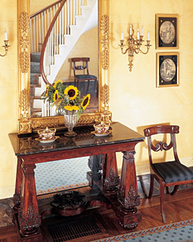 Both the giltwood overmantel mirror and this pier table were made in Boston, circa 1830. The table is one of only a handful of similar tables produced in this area. None bear a maker's signature but this one is a wonderful example of Egyptian influence in Classical furniture. A set of late-eighteenth-century mezzotints of the four continents (two shown) hangs above a finely carved klismos-form dining chair from Boston, 1820. It is one of a set passed down from Mary Lyman Eliot to her son, former Harvard president Charles Eliot (1834-1926). Klismos is an ancient Greek chair form characterized by a broad, curving crest rail and saber front and rear legs.
