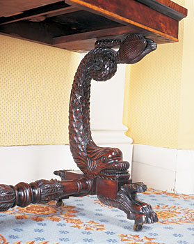 A Sheffield plated tea urn with sphinx finial and Egyptian caryatid columns sits on a New York marble-top pier table. The candleholders are French. Nineteenth-century artist Catherine Davis depicted the Massachusetts State Capitol Building (erected 1795-1798) before its dome was gilded; John Hancock's brick house, since demolished, is to the side.