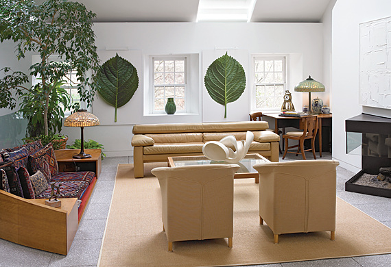 Two sky lights flood the room with light in the daytime and Tiffany lamps, circa 1910, and recessed lighting illuminate the space at night. The images of large green hydrangea leaves picked from the Fernside garden were photographed by Tom Crane of Bryn Mawr. The leaf motif is echoed in the Grueby vase on the window sill. The sand color of the upholstery and sisal rugs continue the inside outside garden theme of the house as does the ficus tree. In the living room, dining room, and hallways, oriental carpets replace the summer rugs in winter.