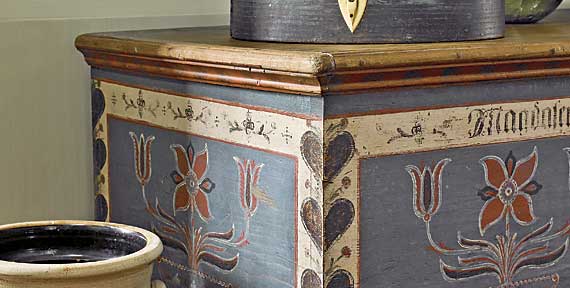The blue-painted carrier and Pennsylvania dower chest from the previous image are shown with a cobalt-decorated New York stoneware churn stamped “Maker-M. Woodruff, Cortland.”
